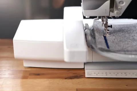 Modern computerised sewing machine with embroidery unit standing on table Stock Photos