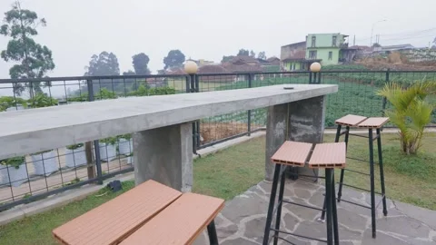 Modern concrete bar table and stools on a scenic outdoor terrace overlooking a m 库存影片 343385911