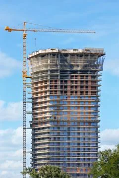 Modern construction of a multi-storey skyscraper with a tower crane on a summ Stock Photos