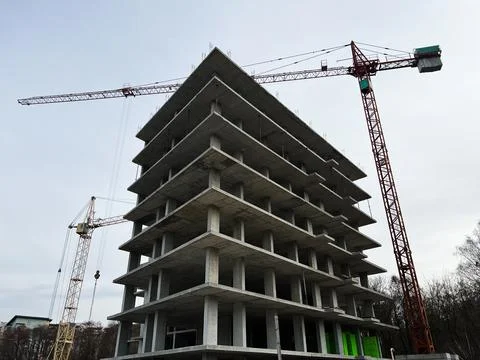 Modern construction site with building framework and cranes under cloudy sky Fotos de archivo