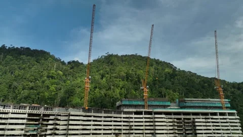 Modern Construction Site Surrounded by Lush Green Mountains and Clear Blue Sky Stock Footage 316450354