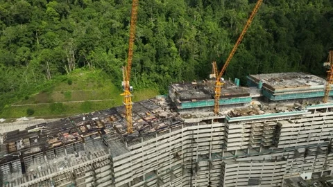 Modern Construction Site with Tower Cranes Surrounded by Lush Green Trees in a Stock Footage 316450351