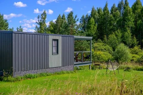 Modern container-style cabin sits in grassy field. Blue sky with scattered .. Stock Photos