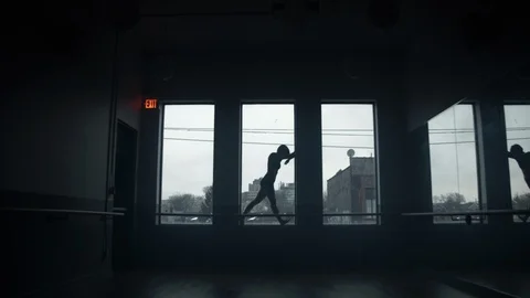 Modern contemporary dancer dancing on window sill in large dark dance studio 스톡 동영상 104275037