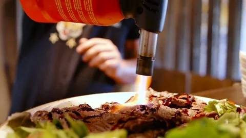 Modern cook warms meat with cooked burner Stock-Footage 78730856