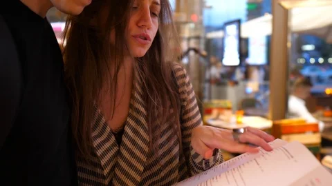 Modern cople checking a menu in a restaurant. Man gives a kiss in the end 스톡 동영상 123063405