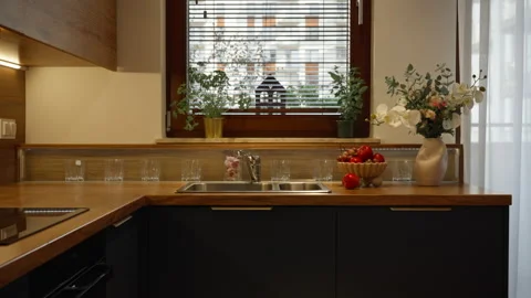 Modern corner kitchen layout with sink under window and dark cabinets Stock Footage 347874402