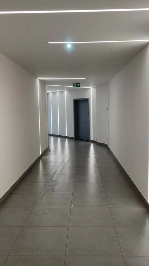 Modern corridor with led strip lights moving toward closed grey door interior 库存影片 341661383