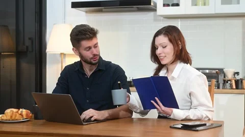 Modern couple collaborating over coffee in a cozy kitchen setting with a la.. Stock Footage 312981032