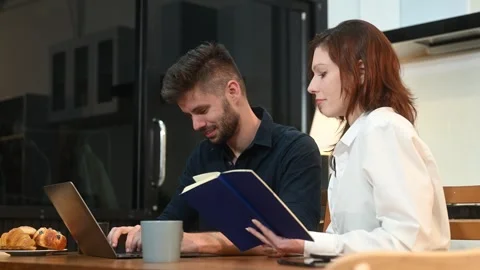 Modern couple collaborating over coffee in a cozy kitchen setting with a la.. Stock Footage 312981036