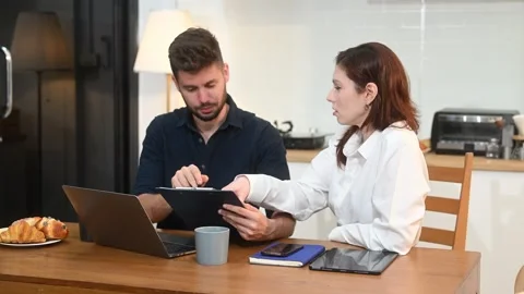 Modern couple collaborating over coffee in a cozy kitchen setting with a la.. Stock Footage 312981080