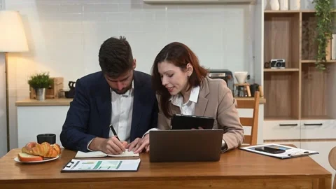 Modern couple collaborating over coffee in a cozy kitchen setting with a la.. Stock Footage 312981119
