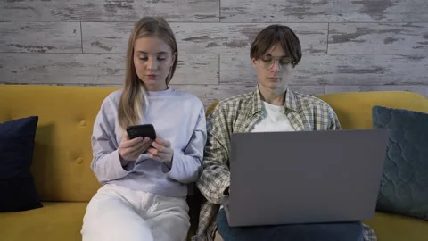 Modern couple on the couch using gadgets: a laptop and a smartphone Vídeos de archivo 259274307