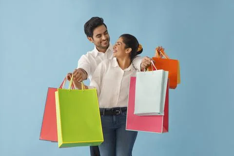 A MODERN COUPLE LOVINGLY LOOKING AT EACH OTHER WHILE HOLDING SHOPPING BAGS	 Foto stock
