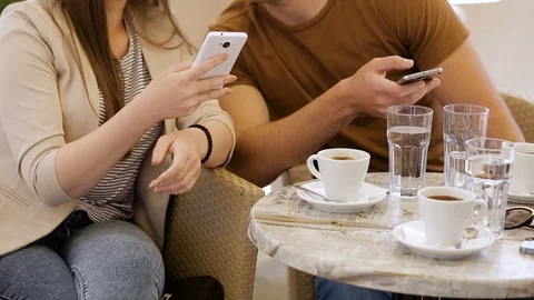 Modern couple sitting in caffe and typing on mobile phone Stock Footage 87392844