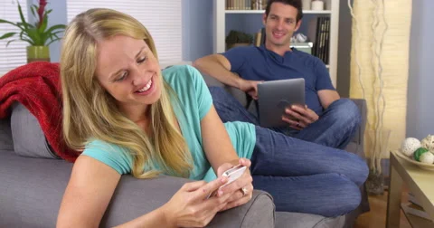 Modern couple using their gadgets on couch Video stock 44479875