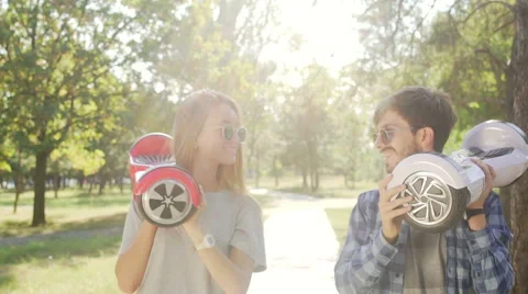 Modern couple walking with hoverboard. Kidding  and kissing. Stock Footage 68917237