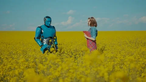 Modern cyborg presenting flowers to young pretty woman farmer standing together Stock Footage 133290758