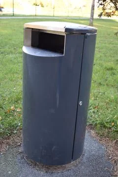 Modern Cylindrical Dark Grey Public Trash Bin in a Par Stock Photos