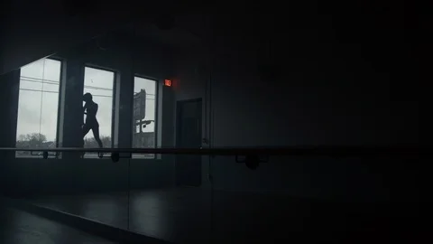 Modern dancer dances in front of large window in silhouette in studio Vídeo Stock 104274216