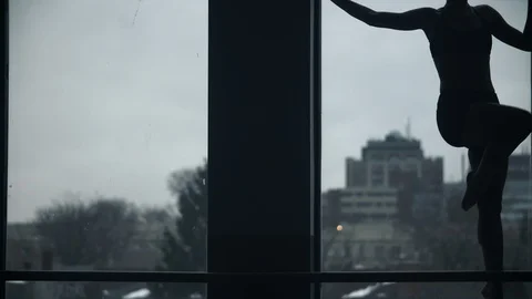 Modern dancer dances in front of large window in silhouette in a dance studio 스톡 동영상 104274222