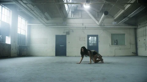 Modern dancer dances in industrial warehouse and falls to the ground Stock Footage 104459752