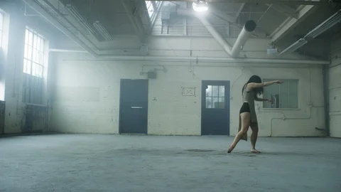Modern dancer dances in industrial warehouse and falls to the ground 스톡 동영상 104461196