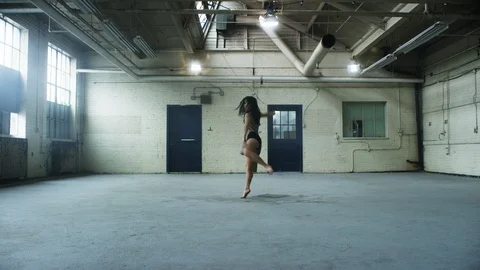 Modern dancer dances with passion and lots of energy, twirls, in warehouse 스톡 동영상 104452156