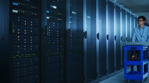 In the Modern Data Center: IT Engineer Working with Server Racks, Uses Laptop 库存影片 101688371