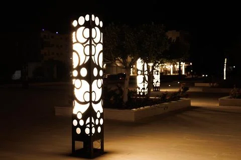 Modern decorative light posts illuminate a night plaza Stock Photos