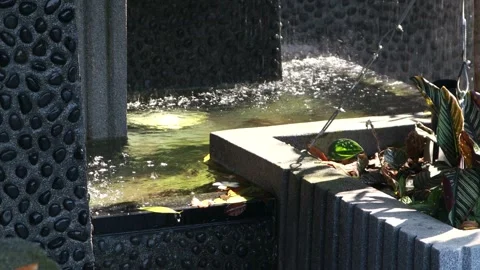 Modern decorative water feature with cascading waterfall in landscaped garden Stock Footage 337494731