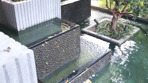 Modern decorative water feature with cascading waterfall in landscaped garden Stock Footage 337494732