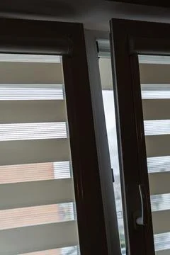 Modern design of opened window with striped roller blinds, allowing natural Stock Photos