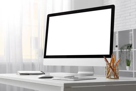 Modern desktop computer with blank white screen on minimalist office desk, ho Stock Photos