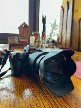 Modern digital camera in black with a large lens on a wooden table. Fotos Stock