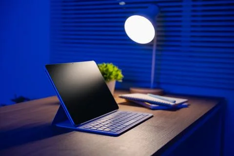 Modern digital tablet with wireless keyboard on wooden desk illuminated by .. Stock Photos