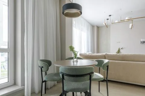 Modern Dining Area Interior with Round Table and Green Upholstered Chairs Stock Photos