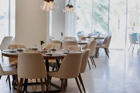 Modern dining area with multiple tables set with white dishes and silverware. Stockfoto's