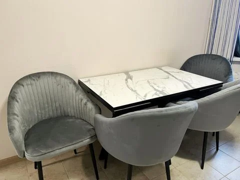 Modern dining set with marble-pattern table and grey velvet chairs. Stock Photos