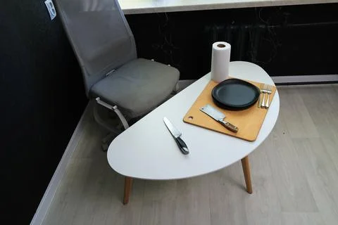 Modern dining setup with black plates, knives, and forks on a white table Stock Photos