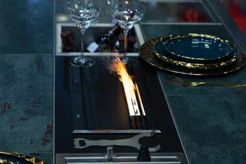 Modern dining table with fire feature and elegant tableware setup Stock Photos