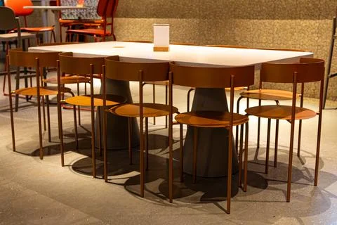 Modern dining table set with orange chairs in a cozy restaurant setting Stock Photos