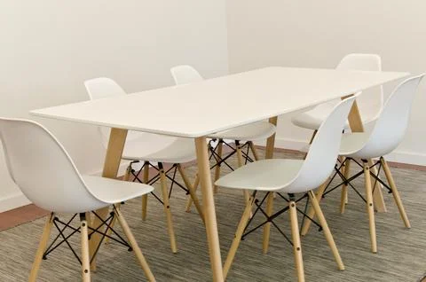 Modern dining table with six white chairs in minimalist room, clean lines Stock Photos