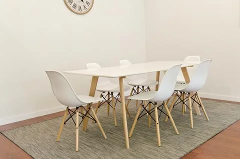 Modern dining table with six white chairs in minimalist room, clean lines Stock Photos
