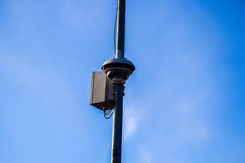 Modern Dome Security Camera and Control Box on Metal Pole Against Blue Sky Stock Photos
