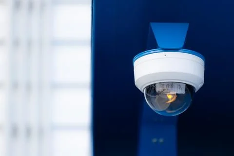 A modern dome security camera with a blue protective cover mounted Foto stock