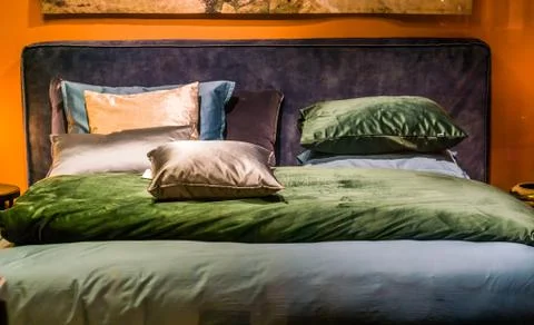 Modern double bed with sheets and pillows in diverse colors, bedroom interior Stock Photos