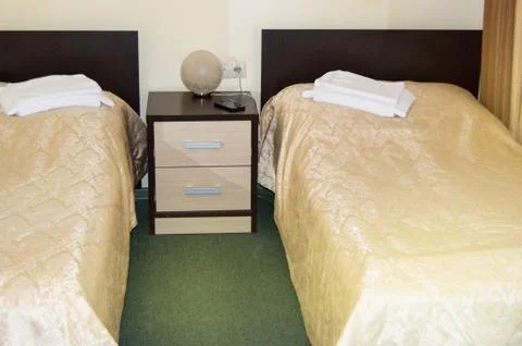 Modern double room with two single beds, bedside table, towels and table lamp Foto stock