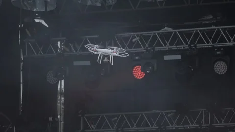Modern Drone quadcopter with camera flying and shoots a concert on stage Video stock 92944865