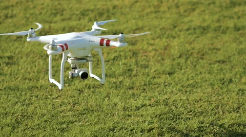 Modern drone taking off and flying above green grass lawn in sunny day. Stock Footage 61450618